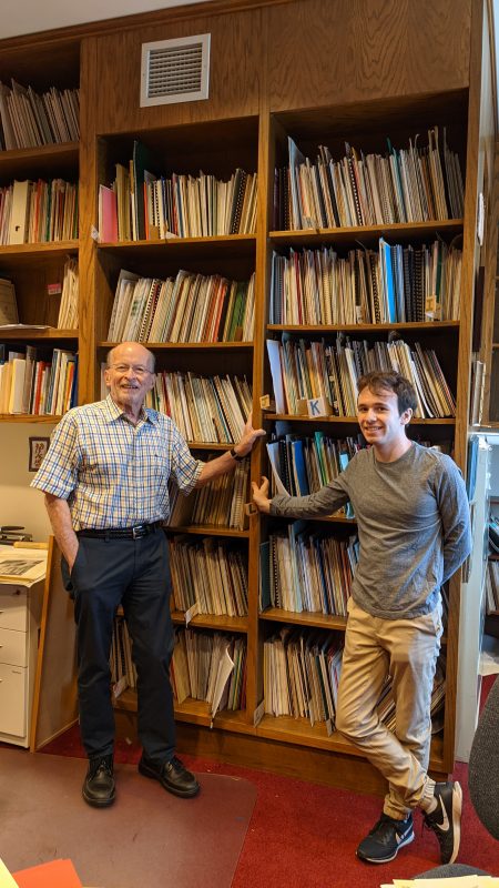 Philip Brunelle and Aaron Schondorf pose in front of shelves of music.