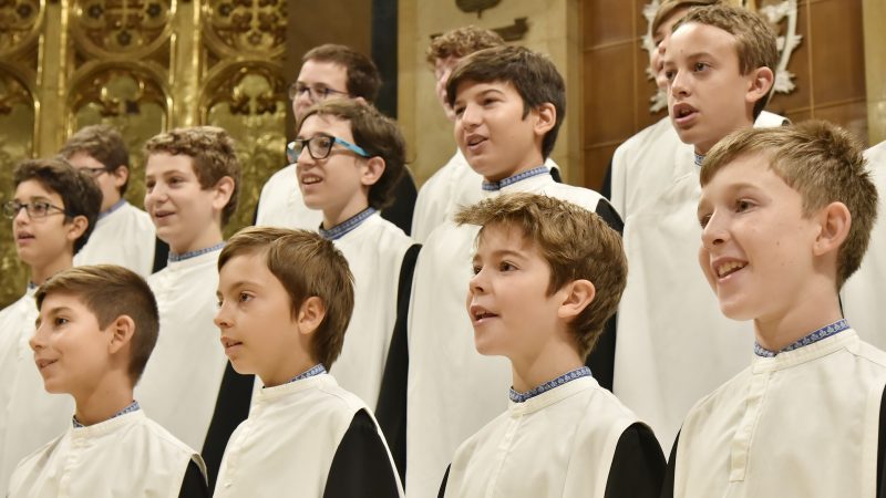 Montserrat Boy Choir members in cassocks singing