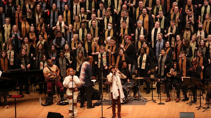 A large group of singers wearing stoles perform on the Orchestra Hall stage. Photo Credit: Kyndell Harkness