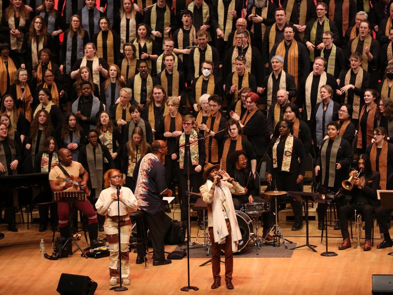 A large group of singers wearing stoles perform on the Orchestra Hall stage. Photo Credit: Kyndell Harkness