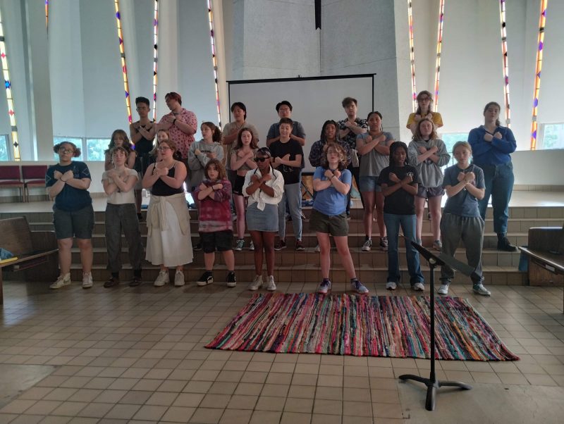 Singers with their hands crossed over their hears performing.