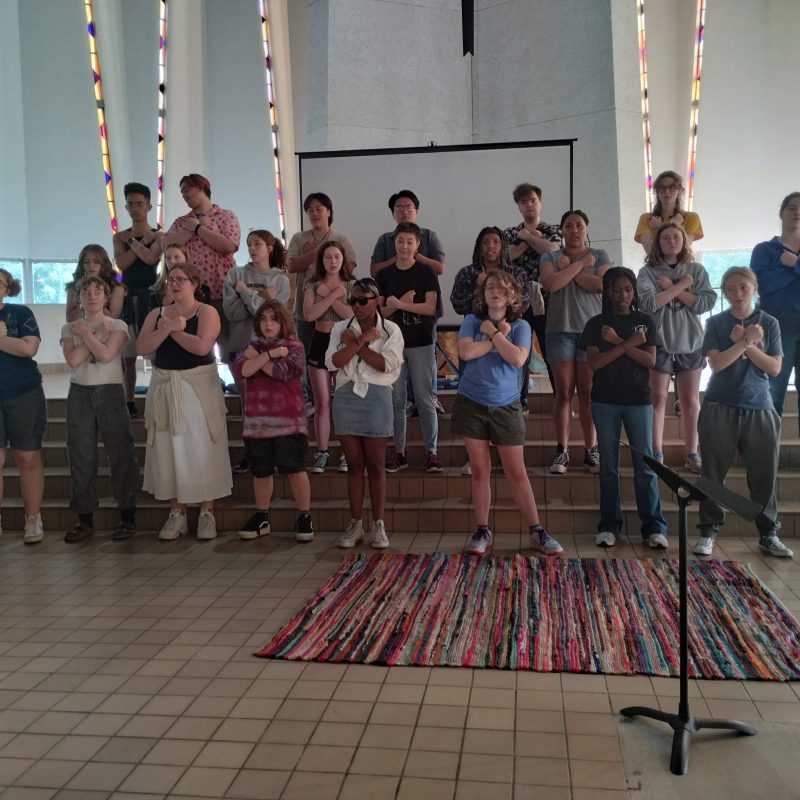 Singers with their hands crossed over their hears performing.
