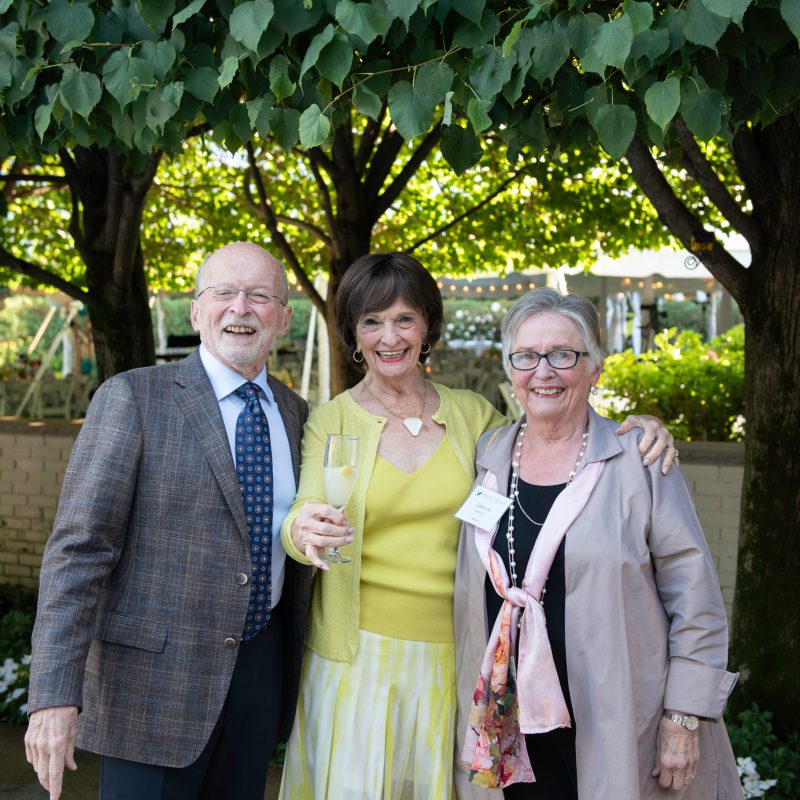 Philip Brunelle, Marilyn Carlson Nelson, and Carolyn Brunelle pose for a photo in front of trees. Photo credit: Bruce Silcox