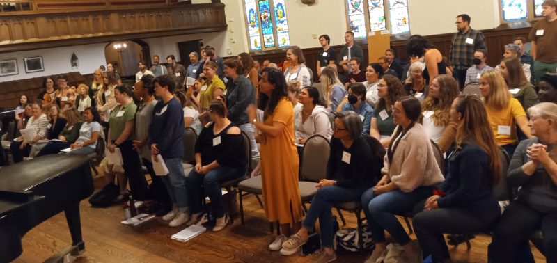 VocalEssence singers are standing and sitting looking toward the conductor. Photo credit: Azure Anderson