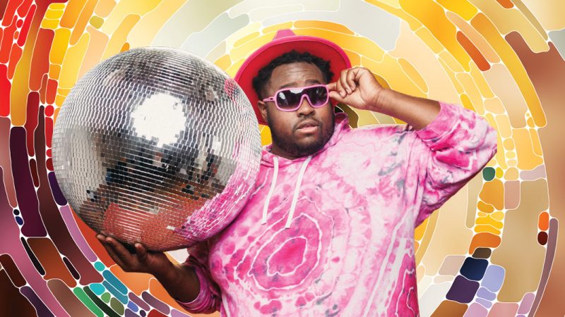 Hip-hop artist Nur-D, wearing a pink tie-dye shirt, pink hat, and pink sunglasses, holding a large disco ball, on a multi-colored background that imitates the disco ball design.