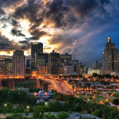 The skyline of downtown Saint Paul, Minnesota with a sky of dark storm clouds and hints of the sun breaking through. Photo Credit: Dan Anderson.