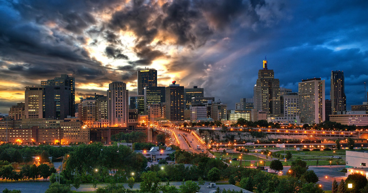 The skyline of downtown Saint Paul, Minnesota with a sky of dark storm clouds and hints of the sun breaking through. Photo Credit: Dan Anderson.