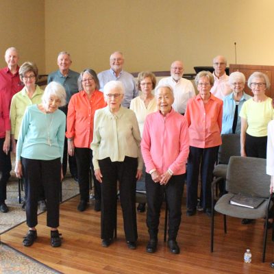 Vintage Voices Singers pose for a group photo wearing pastel colored tops and black pants. Photo credit: Tonia Swennes