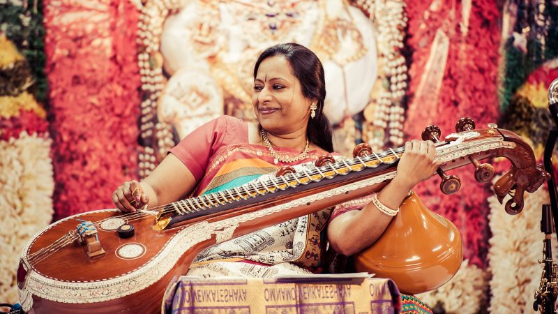 Nirmala Rajasekar sits playing the veena, a plucked string instrument. Photo Credit: ReyMash Photography