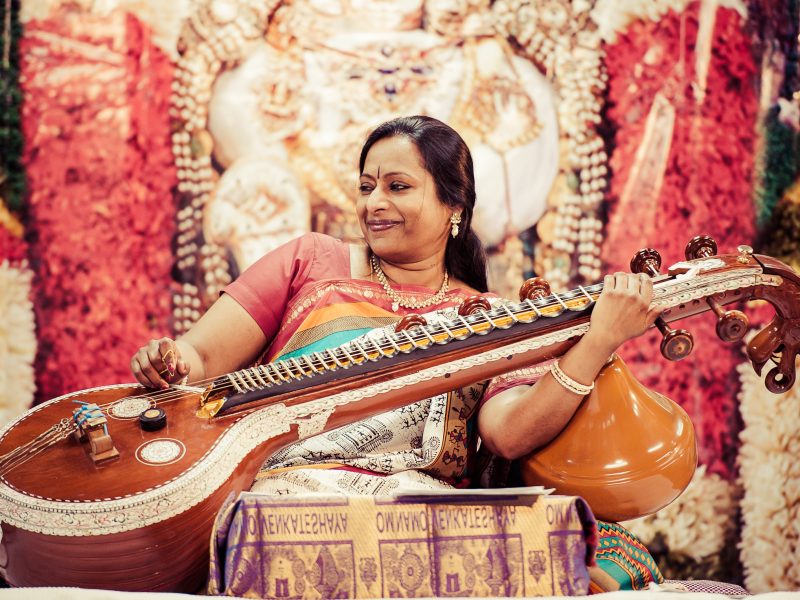 Nirmala Rajasekar sits playing the veena, a plucked string instrument. Photo Credit: ReyMash Photography