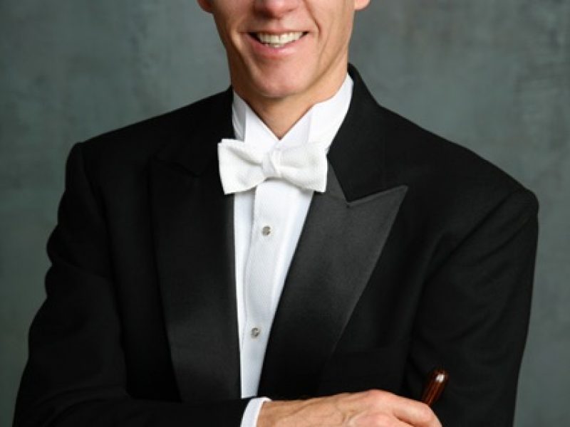 Person in black tuxedo holding a baton..