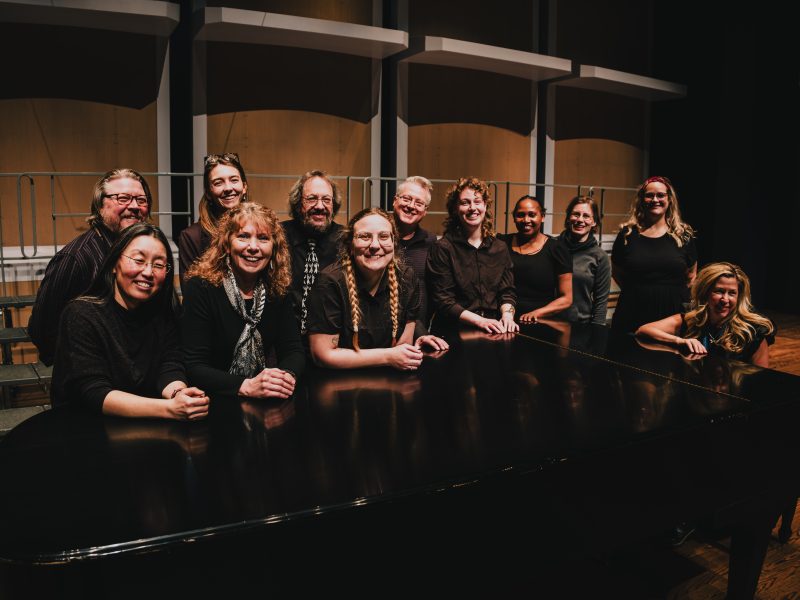 Minneapolis Public School Teachers standing around a piano and smiling. Photo credit: Ethan Kellum-Johnson