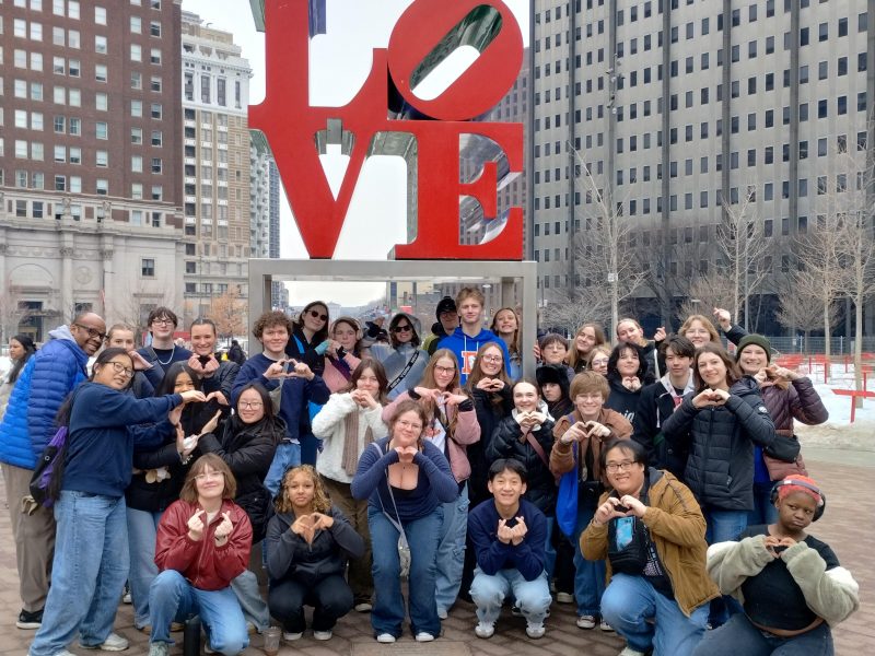 People standing around a "LOVE" statue in red.