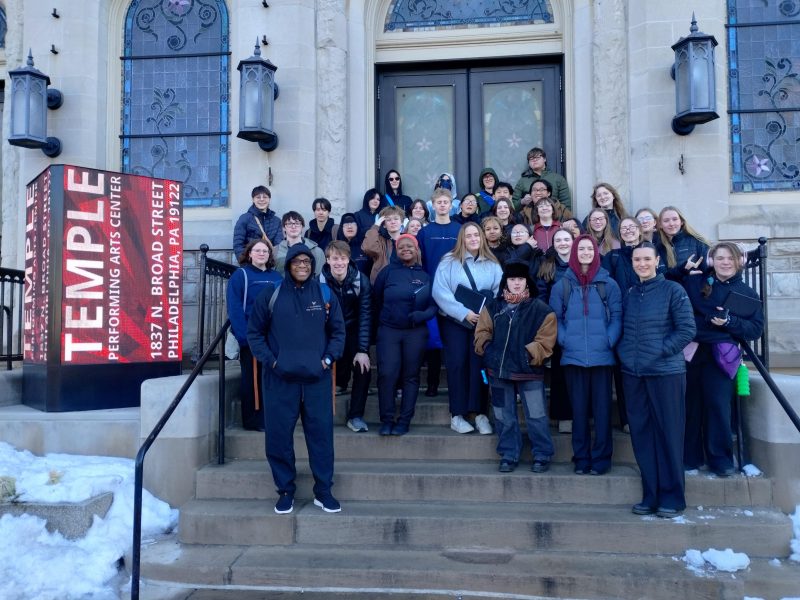 SOTA singers pose for a photo on the steps in front of a building.
