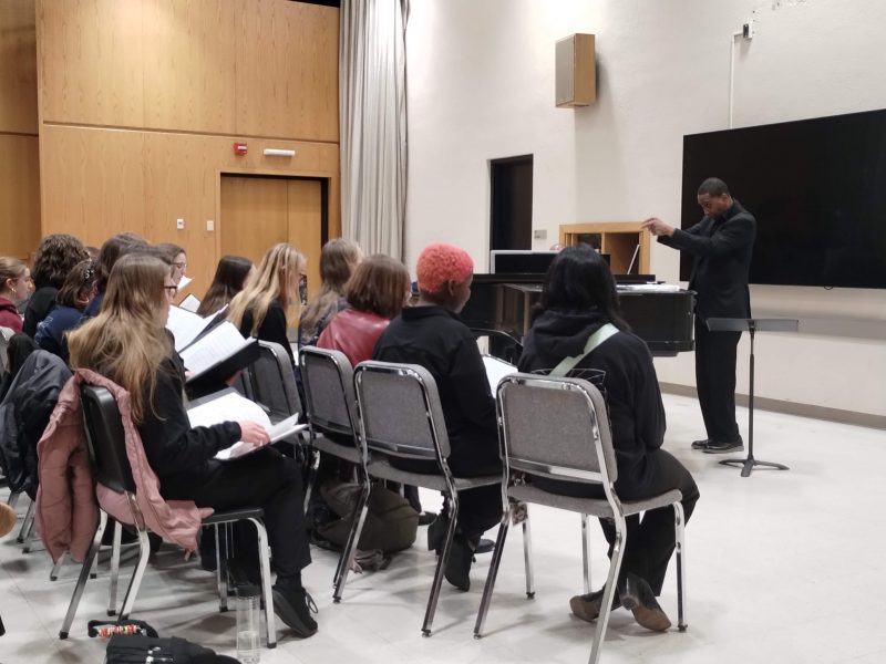 SOTA singers sitting in chairs with Dr. Rollo Dilworth conducting them.
