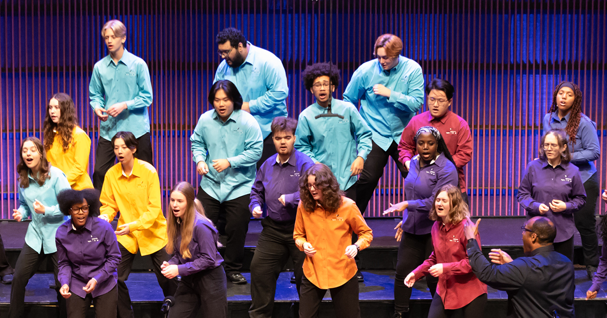 Members of VocalEssence Singers Of This Age wearing multicolored shirts and black pants singing and dancing on risers. Photo credit: Anna Min