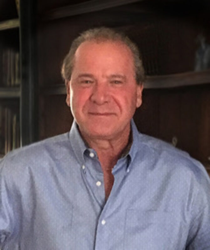 Person with short hair wearing a light blue button down shirt.